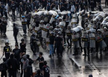 SURABAYA, INDONESIA - MARCH 24: Activists clash with Indonesian Police officers during a protest against the military law revision on March 24, 2025 in Surabaya, Indonesia. On March 20, Indonesia's House of Representatives passed a revision to military law, allowing military officers to serve in more government posts and take up civilian positions without resigning from the Indonesian National Armed Forces. This amendment has drawn criticism from civil society groups, who warn it could signal a return to the repressive New Order era under former President Soeharto, when military officers dominated civilian affairs.Critics argue that this change could lead to abuse of power, human rights violations, and political impunity for army personnel, reminiscent of the era under dictator Suharto, who stepped down in 1998. The timing is particularly significant as Indonesia is now led by President Prabowo Subianto, an ex-special forces general and former son-in-law of Suharto, who was inaugurated in October 2024. (Photo by Robertus Pudyanto/Getty Images)