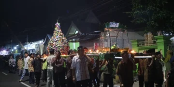 “Masyarakat sedang mengikuti prosesi arak-arakan tumpeng untuk memperingati 1 Suro, sebagai wujud syukur dan pelestarian budaya lokal.”