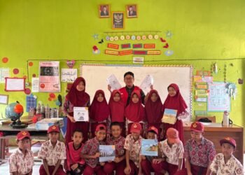 Mahasiswa KKN-T 114 Unhas dan siswa menunjukkan hasil ulasan buku yang mereka buat.