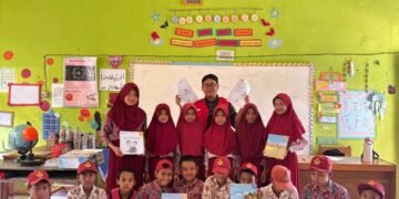 Mahasiswa KKN-T 114 Unhas dan siswa menunjukkan hasil ulasan buku yang mereka buat.