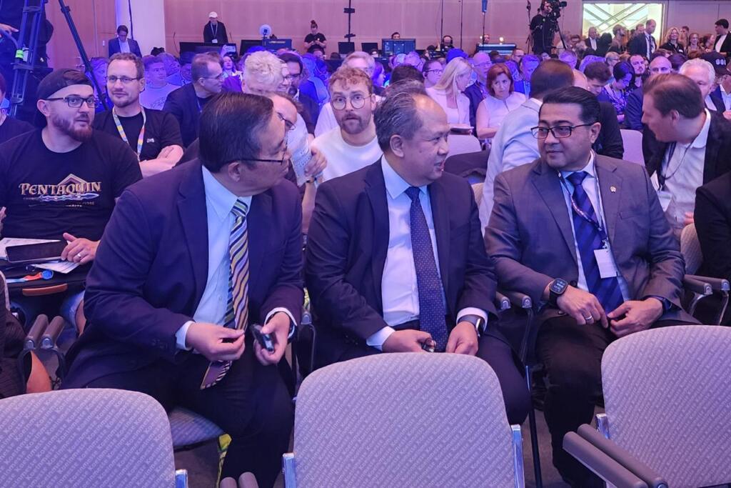 Menteri Ekraf Bawa Semangat Perkuat Ekosistem Game Nasional di Jerman 2 A group of people seated in a conference setting, engaged in conversation, with a mix of attendees in the background.