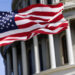 The flag of the united states of america flying in front of the capitol building blurred in the background. United states federal congress on Capitol hill in Washington D.C. Democracy and freedom.