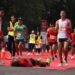 Sejumlah Pelari Tumbang di Garis Finis Alfamart Run 2025 di GBK Akibat Kelelahan 59 Seorang pelari kelelahan tergeletak di garis finish maraton, sementara pelari lain dan petugas berjaket merah/hijau mengawasi.