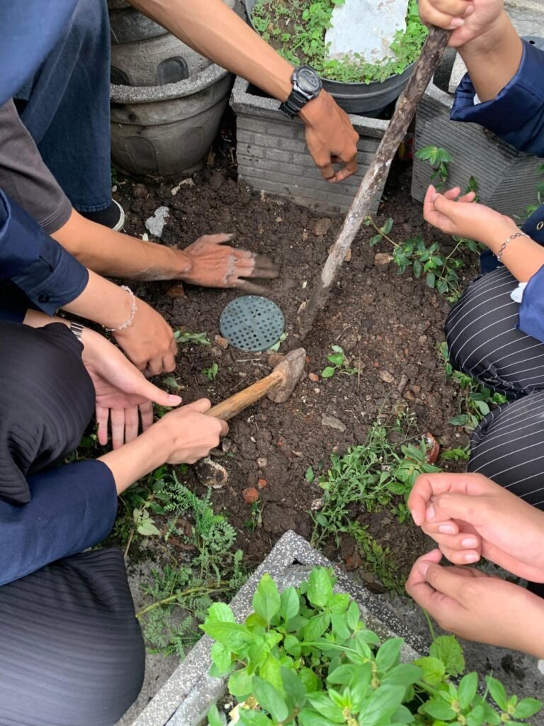 Mahasiswa UNESA dan warga Peneleh bekerja sama menggali tanah untuk membuat lubang resapan biopori.