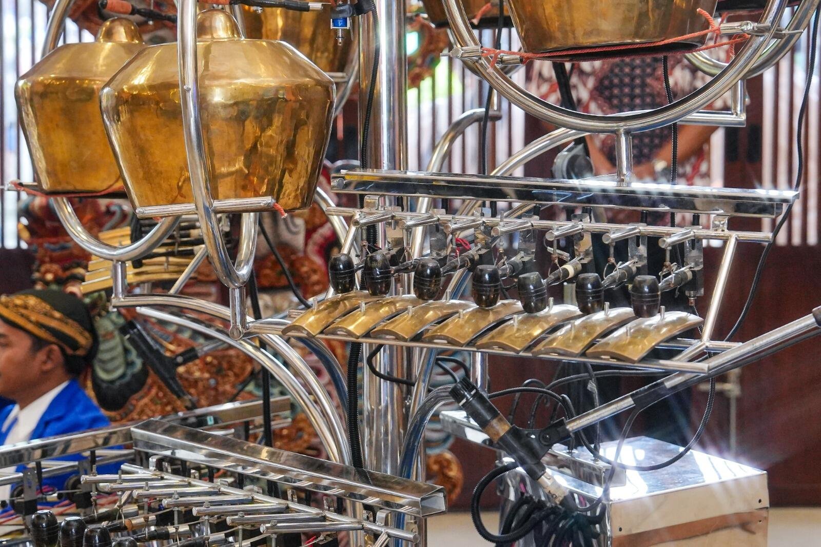 Kementerian Ekraf Luncurkan Robot Gamelan di TMII, Apresiasi Teknologi dan Tradisi 50 A close-up of a traditional musical instrument setup featuring metallic gongs and percussion elements, with a performer in the background.
