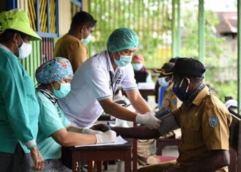 Petugas medis Puskesmas Agats melakukan pemeriksaan kesehatan warga yang akan menerima suntikan vaksin COVID-19 di Ewer, Asmat, Papua, Jumat (2/7/2021). Pemerintah Kabupaten Asmat gencar melaksanakan vaksinasi COVID-19 untuk masyarakat termasuk jemput bola dengan mengerahkan tenaga kesehatan ke kampung-kampung. ANTARA FOTO/Puspa Perwitasari/wsj.