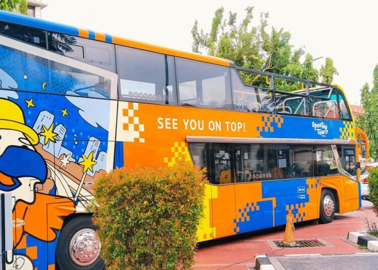 Bus tingkat atap terbuka Jakarta Heritage dari OpenTop Tours sedang berhenti di pinggir jalan Jakarta.