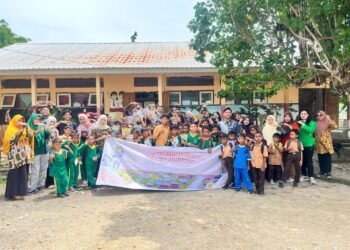 Seluruh siswa SDN Omo bersama guru dan tim relawan Temu Hukum ID berfoto bersama di depan sekolah sambil memegang spanduk program Temu Hukum Berdampak.