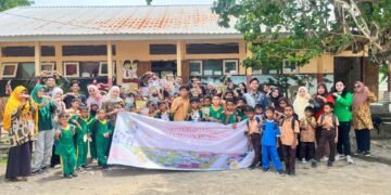 Seluruh siswa SDN Omo bersama guru dan tim relawan Temu Hukum ID berfoto bersama di depan sekolah sambil memegang spanduk program Temu Hukum Berdampak.