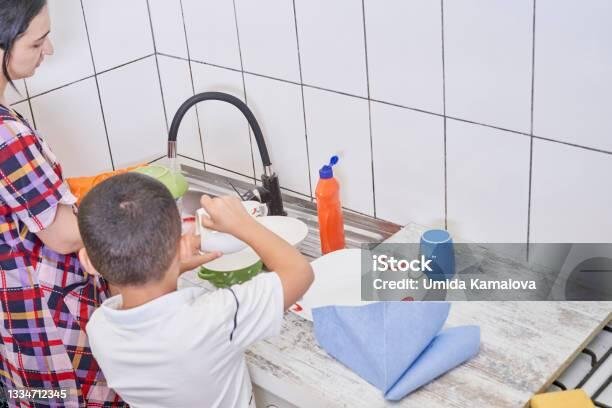 Menggeser Orientasi Pendidikan: Penguatan Life Skill dalam Proses Pembelajaran 46 Son helps mother in the kitchen. Mom and son washing dishes. Indoor shot of cute female with kid in kitchen interior washing dishes. Helping mother to do housework