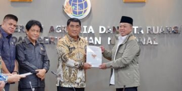 Serahkan Persub RTRW kepada Gubernur Sulawesi Utara, Menteri Nusron Minta RTRW Provinsi Jadi Acuan Penyusunan RTRW Kabupaten/Kota Jakarta - Menteri Agraria dan Tata Ruang/Kepala Badan Pertanahan Nasional (ATR/BPN), Nusron Wahid menyerahkan Surat Persetujuan Substansi (Persub) Rencana Tata Ruang Wilayah (RTRW) Provinsi Sulawesi Utara Tahun 2025-2044 kepada Gubernur Sulawesi Utara, Yulius Selvanus pada Kamis (19/02/2025), di Kantor Kementerian ATR/BPN, Jakarta. Dalam kesempatan tersebut, Menteri Nusron menegaskan bahwa RTRW Provinsi harus menjadi acuan utama bagi penyusunan RTRW Kabupaten/Kota, untuk mencegah tumpang tindih dan penyimpangan pemanfaatan lahan. “Saya minta Pak Gubernur mengontrol bupati dan wali kota. Pertama, yang belum menyusun RTRW segera susun. Kedua, penyusunannya harus selaras, hanya berbeda skala peta. Ketiga, masukkan Lahan Pertanian Pangan Berkelanjutan (LP2B) minimal 87%. Alhamdulillah, di Sulut sudah 91,14%, tinggal diturunkan ke kabupaten/kota. Jangan sampai turun,” ujar Menteri Nusron. Penyertaan LP2B ke dalam RTRW juga sejalan dengan arahan presiden terkait perlindungan lahan sawah yang harus dipertahankan secara permanen dan tidak boleh dialihfungsikan. Ketentuannya, paling sedikit sudah memetakan 87% untuk LP2B. Di Sulawesi Utara sendiri, dari total 15 kabupaten/kota, baru ada tiga daerah yang telah memiliki RTRW. Dengan begitu, masih terdapat 12 kabupaten/kota yang perlu segera menyusun dan menyesuaikan dokumen tata ruangnya. “Semoga pertemuan ini bukan yang terakhir karena kita masih harus menindaklanjuti RTRW Kabupaten/Kota. Bicara RTRW berarti kita bicara masa depan,” tutur Menteri Nusron. Menteri Nusron menjelaskan, perbedaan antara RTRW Provinsi dan RTRW Kabupaten/Kota hanyalah dalam skala petanya. Pada tingkat provinsi, peta yang digunakan berskala 1:250.000. Sementara itu, peta RTRW Kabupaten menggunakan skala 1:50.000, dan RTRW Kota 1:25.000. Skala yang lebih mendetail dituangkan dalam bentuk Rencana Detail Tata Ruang (RDTR) untuk peta tingkat kecamatan dengan skala 1:5.000. Usai Persub Sulawesi Utara Tahun 2025-2044 diserahkan oleh Menteri Nusron, Gubernur Sulawesi Utara, Yulius Selvanus, menyampaikan rasa syukur atas terbitnya dokumen yang telah dipersiapkan sejak 2019. Persub tersebut selanjutnya akan ditindaklanjuti menjadi Peraturan Daerah Provinsi Sulawesi Utara. “Harapan pemerintah, DPR, dan masyarakat Sulawesi Utara benar-benar bertumpu pada RTRW ini. Dengan RTRW yang sudah resmi dan tidak berubah-ubah, investor akan semakin yakin untuk masuk. Hari ini kita resmi memiliki RTRW baru, dan ini menjadi dasar pembangunan Sulawesi Utara ke depan,” ucap Yulius Selvanus. (MW/YZ) #KementerianATRBPN #MelayaniProfesionalTerpercaya #MajuDanModern #MenujuPelayananKelasDunia Biro Hubungan Masyarakat dan Protokol Kementerian Agraria dan Tata Ruang/ Badan Pertanahan Nasional