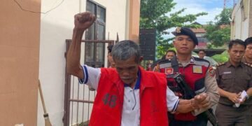 Sorbatua Siallagan, mengangkat dan mengepalkan tangan saat berada di Pengadilan Negeri (PN) Simalungun.
(Sumber: Dok. BAKUMSU via Kompas.com)