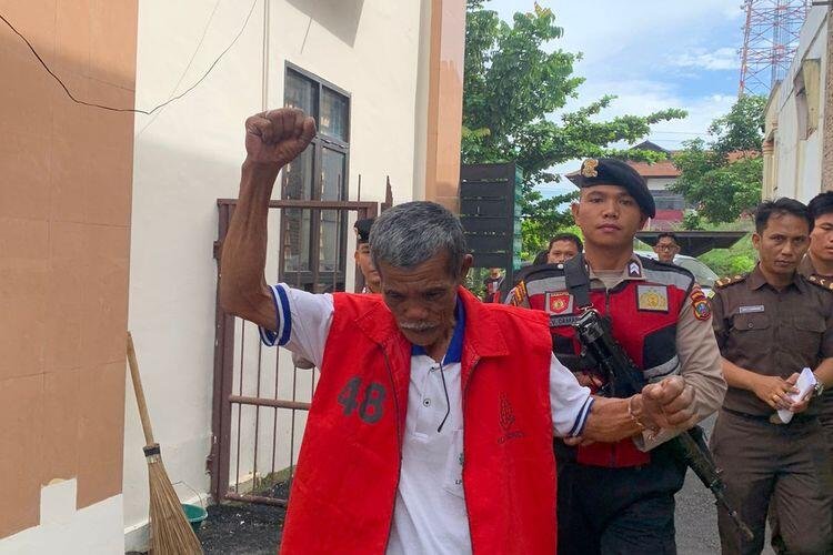Sorbatua Siallagan, mengangkat dan mengepalkan tangan saat berada di Pengadilan Negeri (PN) Simalungun.
(Sumber: Dok. BAKUMSU via Kompas.com)