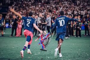 Mimpi Buruk di Budapest: Arsenal Gagal Ukir Sejarah, Dominasi Inggris di Eropa Terhenti 47 Achraf Hakimi dan Ousmane Dembélé berlari membawa trofi UCL di lapangan (Sumber: Instagram/Ousmane Dembele)