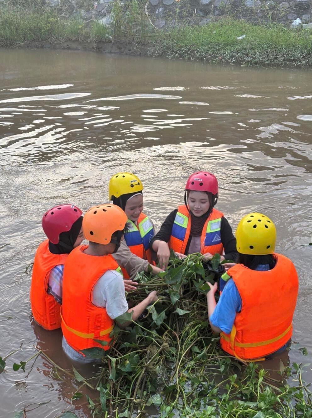 Mahasiswa PADP UNY bersama komunitas Semar Rafting saat mengangkat tanaman liar di aliran Selokan Mataram (Sumber: Dokumentasi Pribadi)