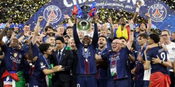 Skuad PSG beserta staff melakukan selebrasi mengangkat trofi UCL di atas podium (Sumber: Instagram/Ousmane Dembele)