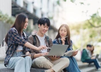 Beautiful young Asian woman college student with friends at outdoors. College student working on the college campus