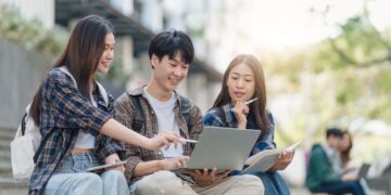 Beautiful young Asian woman college student with friends at outdoors. College student working on the college campus
