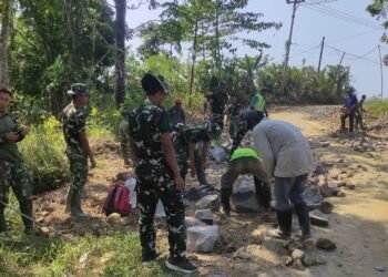 Personel Satgas TMMD Ke-129 Kodim 0601/Pandeglang bersama warga bergotong royong menyusun batu untuk pengerasan badan jalan penghubung Kampung Pangburangan, Desa Pasirgadung dengan Kampung Ciririgi, Desa Simpangtiga, Kecamatan Patia, Kabupaten Pandeglang.
