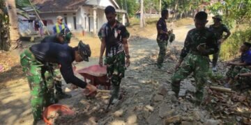 Personel Satgas TMMD ke-129 Kodim 0601/Pandeglang bersama warga bergotong royong melakukan pengerasan badan jalan menggunakan alat manual di Desa Pasirgadung, Kecamatan Patia, Kabupaten Pandeglang.