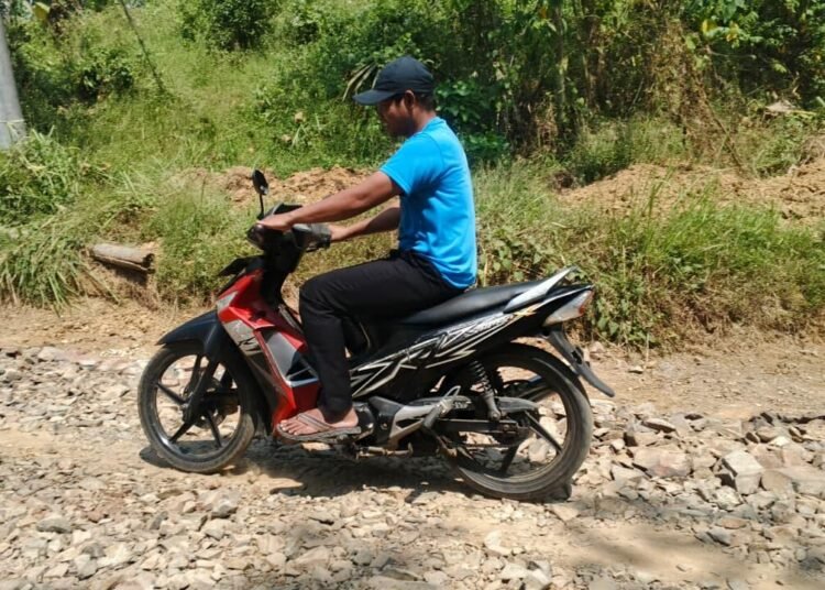 Pengendara sepeda motor melintasi jalan hasil pembangunan TMMD Ke-129 Kodim 0601/Pandeglang di Desa Pasirgadung, Kecamatan Patia, yang kini mempermudah aktivitas dan mobilitas warga.