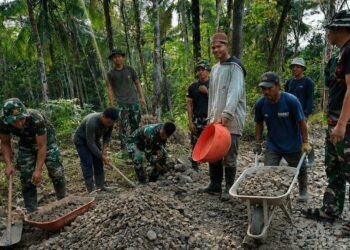 Personel Satgas TMMD Ke-129 Kodim 0601/Pandeglang bersama warga Desa Pasirgadung dan Desa Simpangtiga bergotong royong mengangkut batu serta mengerjakan pembangunan jalan di Kecamatan Patia, Kabupaten Pandeglang, Kamis (30/7/2026).