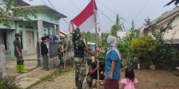 Personel Satgas TMMD Ke-129 Kodim 0601/Pandeglang bersama warga memasang bendera Merah Putih di Kampung Pangburangan, Desa Pasirgadung, Kecamatan Patia, menjelang HUT Ke-81 Kemerdekaan RI.