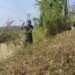 Personel Satgas TMMD melaksanakan pembersihan rumput dan semak belukar di sekitar tenda posko guna menciptakan lingkungan yang bersih, aman, dan nyaman selama pelaksanaan Program TNI Manunggal Membangun Desa (TMMD).