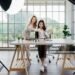 Dua wanita Asia membuat konten untuk media sosial. Mereka menggunakan pengaturan studio yang mencakup smartphone yang dipasang di tripod, peralatan pencahayaan, dan berbagai produk riasan yang tersusun di atas meja.
(Sumber: iStock).