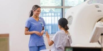 Keterangan foto: Ilustrasi radiografer perempuan yang bekerja menggunakan peralatan radiologi dengan menerapkan prosedur keselamatan radiasi untuk melindungi diri dari paparan radiasi saat bertugas. {Sumber: iStock).